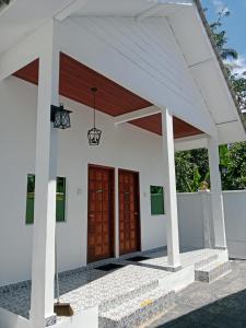 a white house with awning and two wooden doors at Bunohan Villa Roomstay in Tumpat
