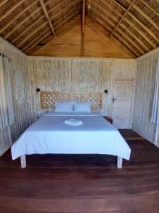 a bedroom with a white bed with a wooden ceiling at Lombok eco Lumbung in Gili Gede