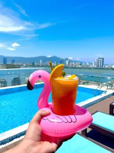 a person holding a pink toy flamingo drink holder at Roliva Hotel & Apartment Danang in Danang