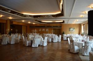 un salón de banquetes con mesas y sillas blancas en Romantik Hotel Schmiedegasthaus Gehrke, en Bad Nenndorf