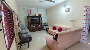 a living room with a couch and chairs and a tv at Estateview Villa Homestay in Sakleshpur