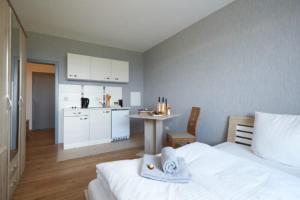 a bedroom with a white bed and a kitchen at Hotel Weimarer Berg in Apolda +26 photos