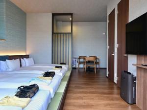 a hotel room with two beds and a flat screen tv at HOTEL SANSUI NAHA Ryukyu Onsen Naminoue-No-Yu in Naha
