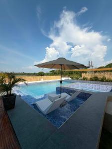 a swimming pool with two chairs and an umbrella at Zensole Resort in Tarlac