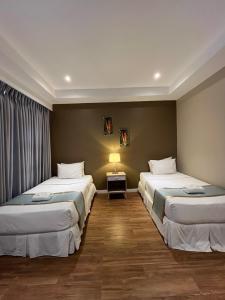 a room with two beds and a table with a lamp at Villa Verde Guest House in General Santos
