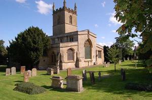 an old church with a clock tower in a cemetery at Stow Lodge Hotel in Stow on the Wold
