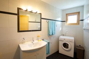ein Badezimmer mit einem Waschbecken und einer Waschmaschine in der Unterkunft Ferienwohnung Neuhäusler, Schinnas Sura 799 in Scuol