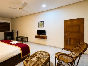 a bedroom with a bed and two chairs and a television at Maple grove villa resort in Panamaram