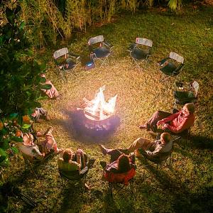 a group of people sitting around a fire in a yard at Bwindi Neckview Lodge in Buhoma +76 photos
