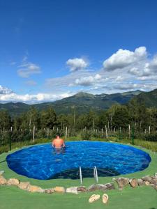 a man in a swimming pool with mountains in the background at Kolibe Ćorić in Mojkovac