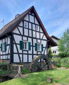 a black and white house with a large wheel at Ferienwohnung Doria in Windeck