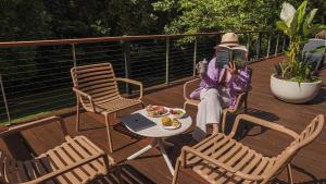 a person sitting on a chair reading a book on a deck at Chambers Wildlife Rainforest Lodges in Lake Eacham