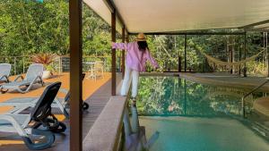 a girl is standing on a skateboard by a swimming pool at Chambers Wildlife Rainforest Lodges in Lake Eacham