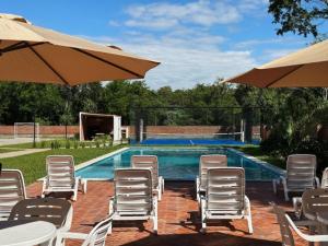 a group of chairs and umbrellas next to a swimming pool at Departamento cerca a Asunción 412 in Luque