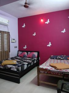 two beds in a room with butterflies on the wall at PR Home Stay in Tiruvidaimarudūr