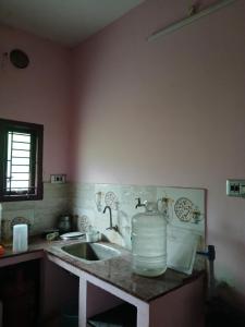 a kitchen counter with a sink and a water jug at PR Home Stay in Tiruvidaimarudūr