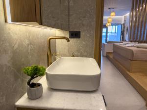 a bathroom with a white sink and a plant on a counter at Marizon Suites - Adults Only in Vrachonisída touArchangélou +18 photos