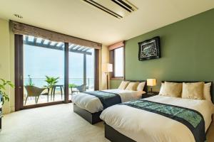 two beds in a room with a large window at ヴィラモンタン・淡路 in Akashi