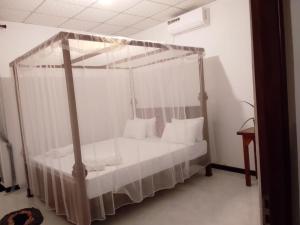 a bedroom with a canopy bed with white sheets and pillows at Wilpattu Coconut Villa in Nochchiyagama