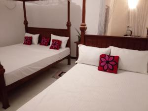 two beds with red and white pillows in a room at Wilpattu Coconut Villa in Nochchiyagama
