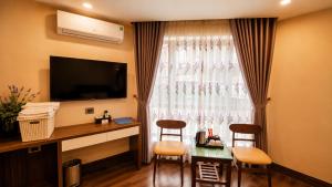 a hotel room with a desk and a window with chairs at Lavender SaPa Hotell & Spa - Free foot soak service in Sapa