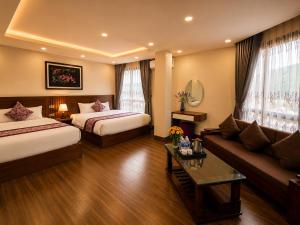 a hotel room with two beds and a couch at Lavender SaPa Hotell & Spa - Free foot soak service in Sapa