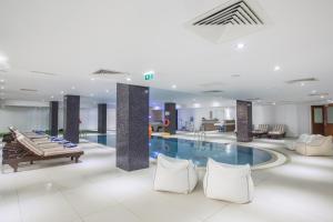 a hotel lobby with a pool and tables and chairs at Anmaria Beach Hotel & Spa in Ayia Napa