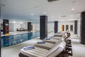 a row of chaise lounge chairs next to a swimming pool at Anmaria Beach Hotel & Spa in Ayia Napa