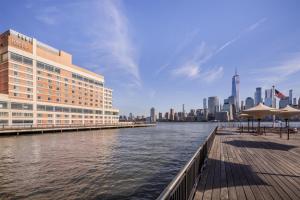 a building next to a body of water with a city at Hyatt Regency Jersey City on the Hudson in Jersey City