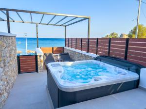 a hot tub on a balcony with the ocean in the background at Marizon Suites - Adults Only in Vrachonisída touArchangélou