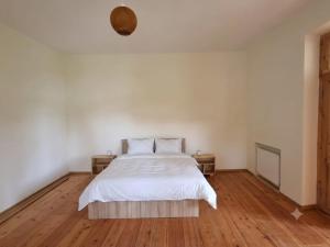 a bedroom with a bed with white sheets and wooden floors at kakhtubani in Chandari