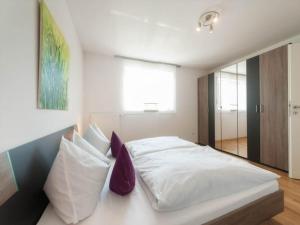 a bedroom with a bed with white sheets and purple pillows at Ferienwohnung Rohrhofer in Tiefenbach