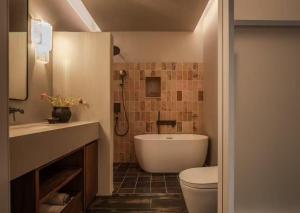a bathroom with a tub and a toilet and a sink at is.land Villa in Sanya