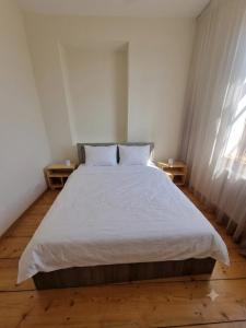 a bedroom with a large white bed with two tables at kakhtubani in Chandari