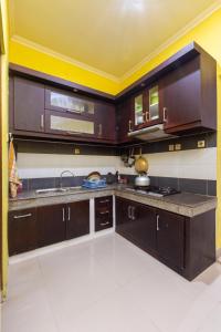 a kitchen with dark wood cabinets and a sink at Homestay Rumahnya Diaz in Kejayan
