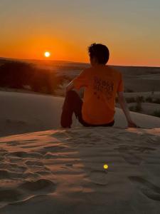 a person sitting on a ledge watching the sunset at Style Heritage Resort & Camp in Sām