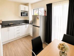 a kitchen with a table and a refrigerator at Midway Pacifica Lodge in Lower Hutt +35 photos