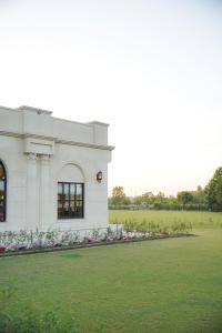 a white building with flowers in front of a field at Alhamra Hotel in Mardan