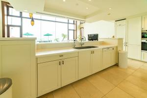 a kitchen with white cabinets and a sink and a window at ヴィラモンタン・淡路 in Akashi