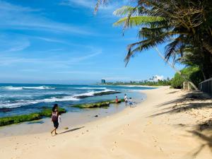 a group of people walking on a beach at Villa Dinusara in Weligama
