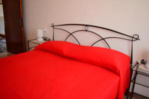 czerwone łóżko z czerwonym kocem w obiekcie Casa Vacanza La Zanca w mieście Zanca