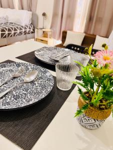 a table with three plates and a vase with flowers at JFam Suites, C4-11K Studio, Up To 4 Pax in Biñan