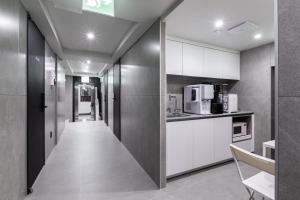 a hallway leading to a kitchen with white cabinets at VIA jongno in Seoul
