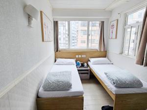 two beds in a room with two windows at K & B Hostel in Hong Kong