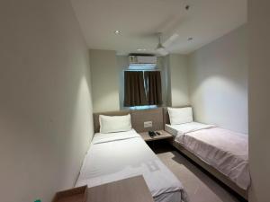 ein kleines Zimmer mit zwei Betten und einem Fenster in der Unterkunft Hotel Miralite in Tinsukia