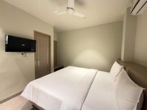 ein Schlafzimmer mit einem weißen Bett und einem Flachbildfernseher in der Unterkunft Hotel Miralite in Tinsukia