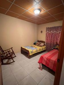 a bedroom with two beds and a chair in it at Comfortable 3-bedroom, 1-kitchen cottage in Cerro Punta