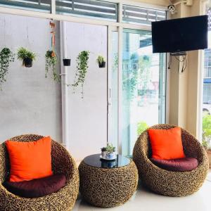 two chairs with orange pillows and a table in front of a window at Ratchanee Place in Chaiyaphum