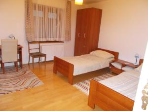 1 dormitorio con 2 camas, escritorio y silla en Guesthouse Ivancica, en Našice