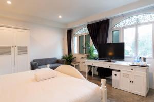 a bedroom with a bed and a desk with a television at Nidhra Lanna Hotel Chiang Mai in Chiang Mai